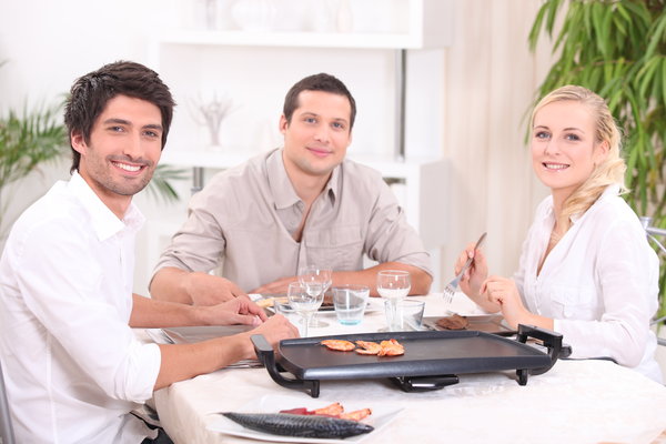 Drei Freunde sitzen um Elektrogrill