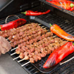 Spieße und Paprika werden auf Gasgrill gedreht