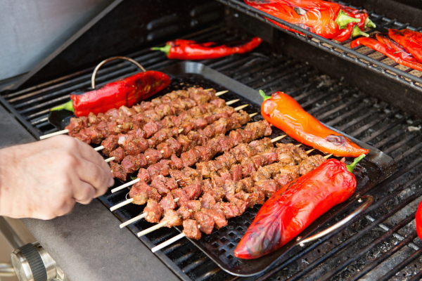 Große Paprika und Spieße werden auf Gasgrill gedreht