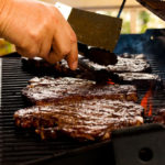 Saftige Steaks auf Gasgrill werden gedreht